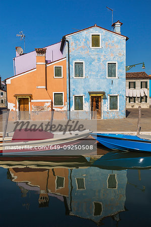 Moored boats on canal lined with orange, mauve and blue stucco houses, Burano Island, Venetian Lagoon, Venice, Veneto, Italy