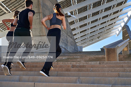 Friends jogging up steps in sports stadium