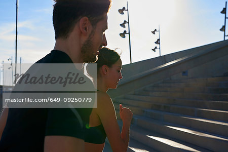 Friends jogging up steps in sports stadium