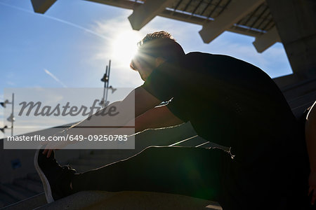 Man stretching on steps in sports stadium