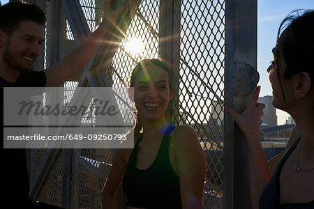 Friends talking beside fenced wall in sports stadium