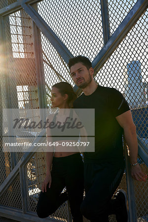 Friends taking break beside fenced wall in sports stadium