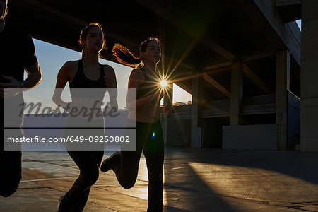 Friends jogging in sports stadium at sunset