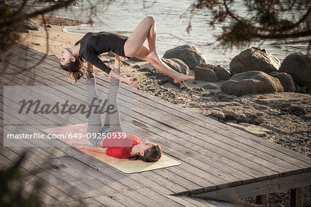Women practising acro yoga at seaside