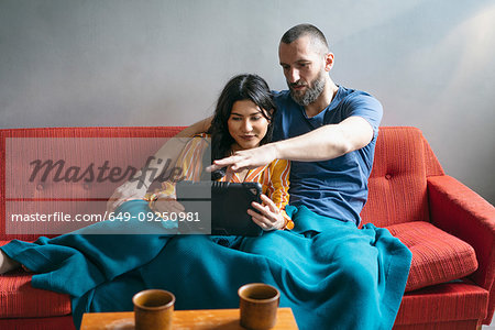 Hipster couple using digital tablet on sofa