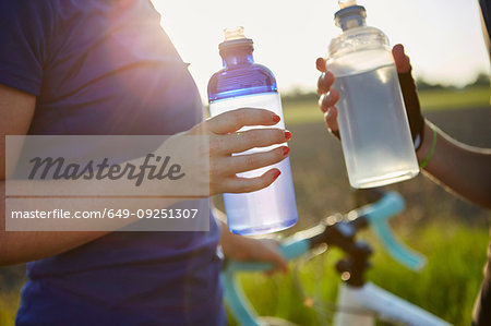 Two female cyclists holding water bottles, mid section