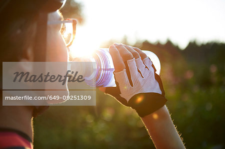 Female cyclist drinking from water bottle, cropped over shoulder view