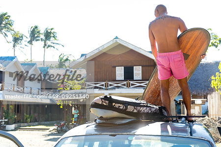Man loading surfboards on top of vehicle, Pagudpud, Ilocos Norte, Philippines