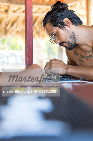 Man using smartphone in beach hut, Pagudpud, Ilocos Norte, Philippines