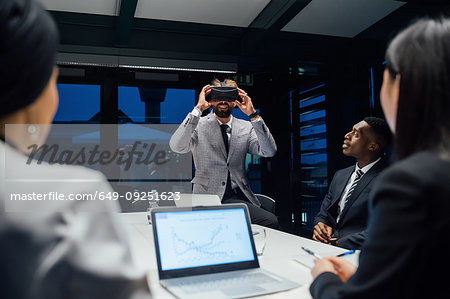 Businessman looking through virtual reality headset during conference table meeting