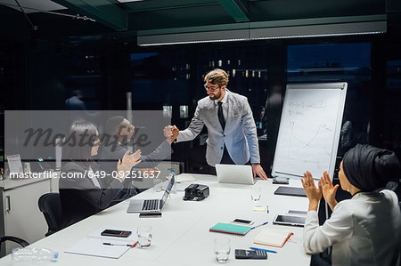 Businessmen and women shaking hands and clapping at office presentation