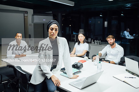 Young businesswoman in front of team at conference table meeting, portrait