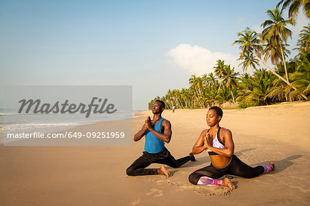 Couple practising yoga on beach