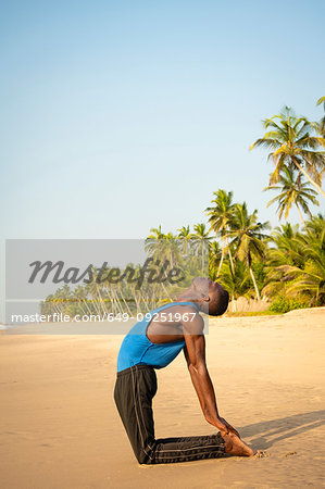 Man practising yoga on beach
