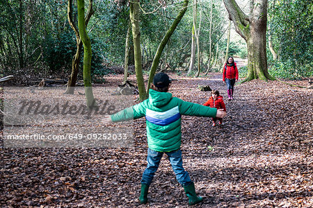 Boy playing with his brother in woodland