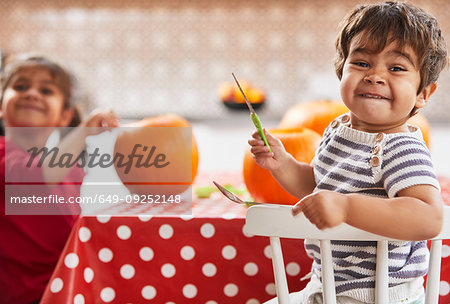 Children carving pumpkin in kitchen