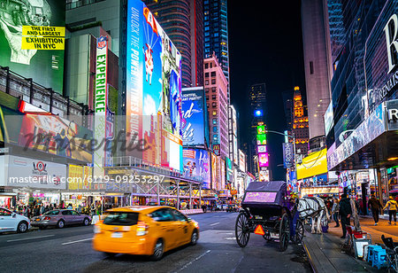 The bright lights of New York City's Times Square with an iconic yellow cab passing through, New York, United States of America, North America