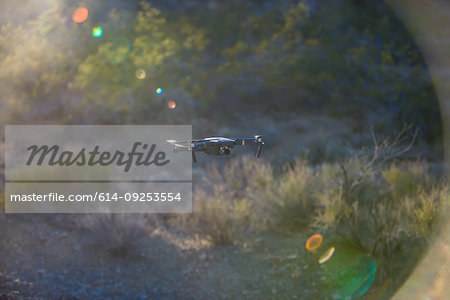 Drone (unmanned aerial vehicle) flying mid air over arid landscape