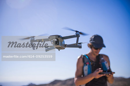 Man operating drone (unmanned aerial vehicle) against blue sky, Nelson, Nevada, USA