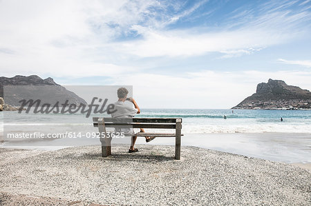 Mature man taking photograph from beach bench, Cape Town, Western Cape, South Africa