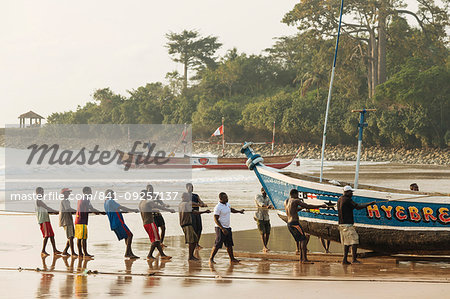 Men pulling boat out to sea, Busua, Ghana, Africa