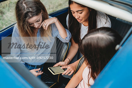 Friends using smartphone inside car