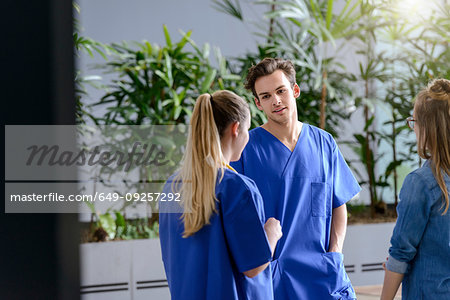 Male and female junior doctors chatting outside hospital