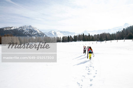 Five teenage girl skiers carrying skis in snow covered landscape, rear view, Tyrol, Styria, Austria