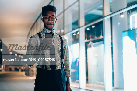 Businessman using smartphone, walking past shopfront, Milano, Lombardia, Italy