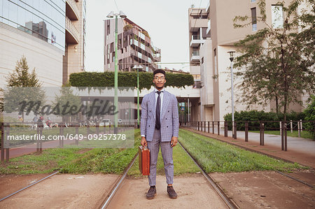 Businessman standing in middle of tram lines, Milano, Lombardia, Italy