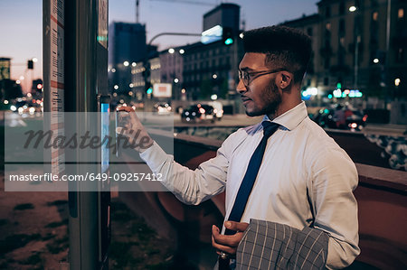 Businessman using digital information system at bus stop, Milano, Lombardia, Italy