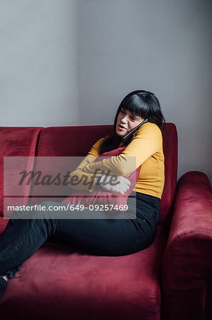 Woman talking on smartphone on sofa