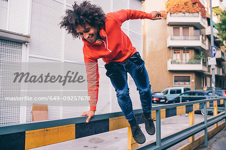 Young man jumping over divider on pavement, Milano, Lombardia, Italy