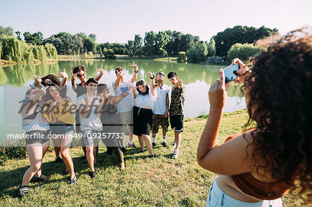 Woman taking photograph of friends by lake