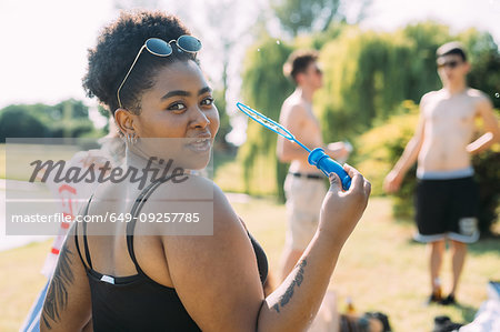 Young woman blowing bubbles in park
