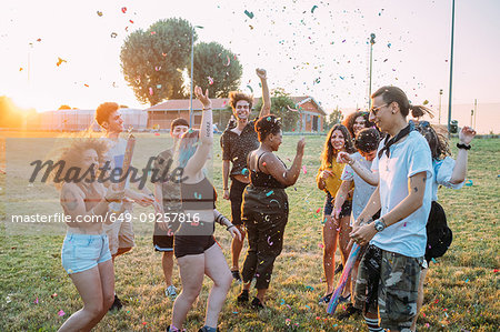 Group of friends dancing, playing with confetti in park