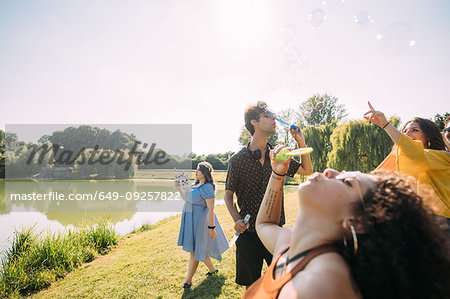 Group of friends blowing bubbles in park