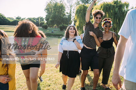 Group of friends dancing, playing guitar in park