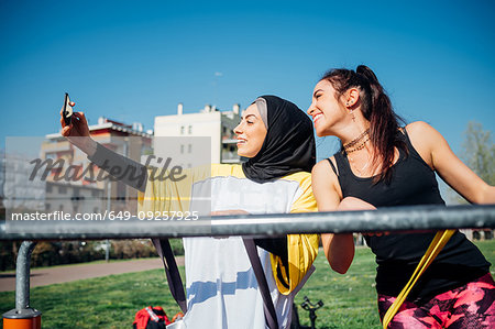 Calisthenics class at outdoor gym, two young women taking smartphone selfie