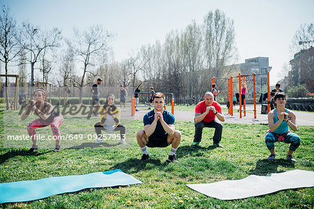 Calisthenics class at outdoor gym, women and men practicing yoga squatting pose