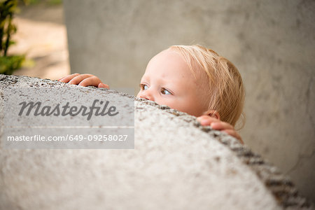 Cute female toddler peering over wall