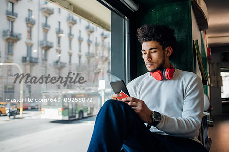 Young man looking at smartphone in cafe window seat