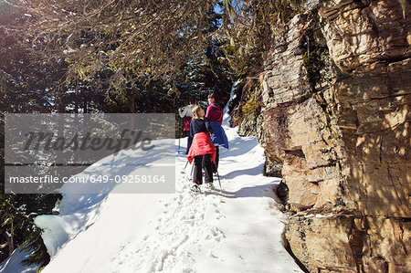Teenage girl and sisters snowshoeing  up snow covered mountainside, Styria, Tyrol, Austria