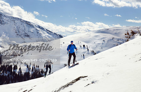 Mature skiing couple moving up snow covered mountain,  Styria, Tyrol, Austria