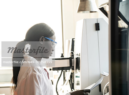 Young female scientist reading notebook in laboratory