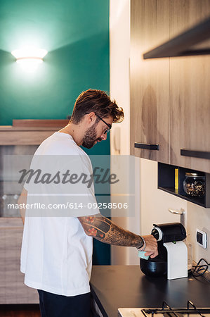 Mid adult man pouring coffee from coffee machine on kitchen counter