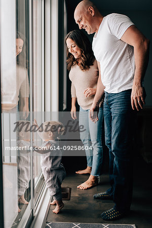 Mother and father with baby daughter looking out through patio door