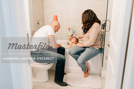 Mother and father playing with baby daughter in bath