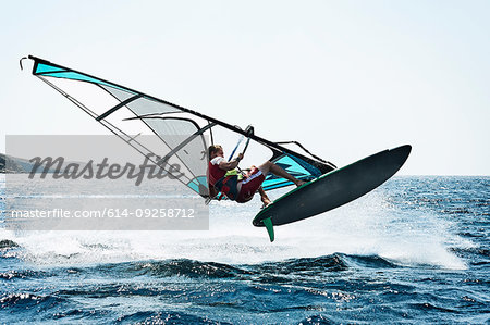 Young man windsurfing above ocean waves, Limnos, Khios, Greece