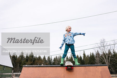 Boy standing on top of skateboard ramp pointing